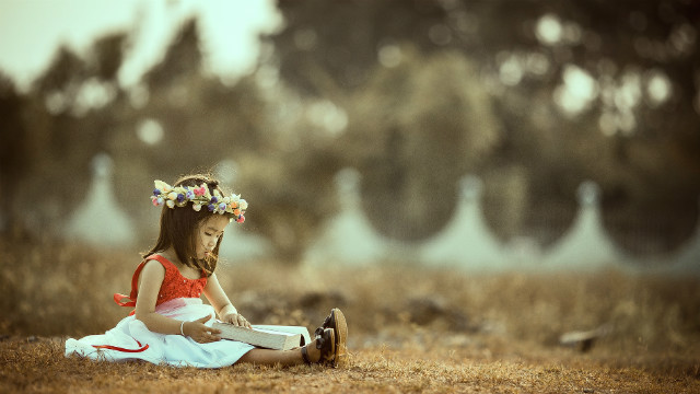 小女孩坐在河邊看書